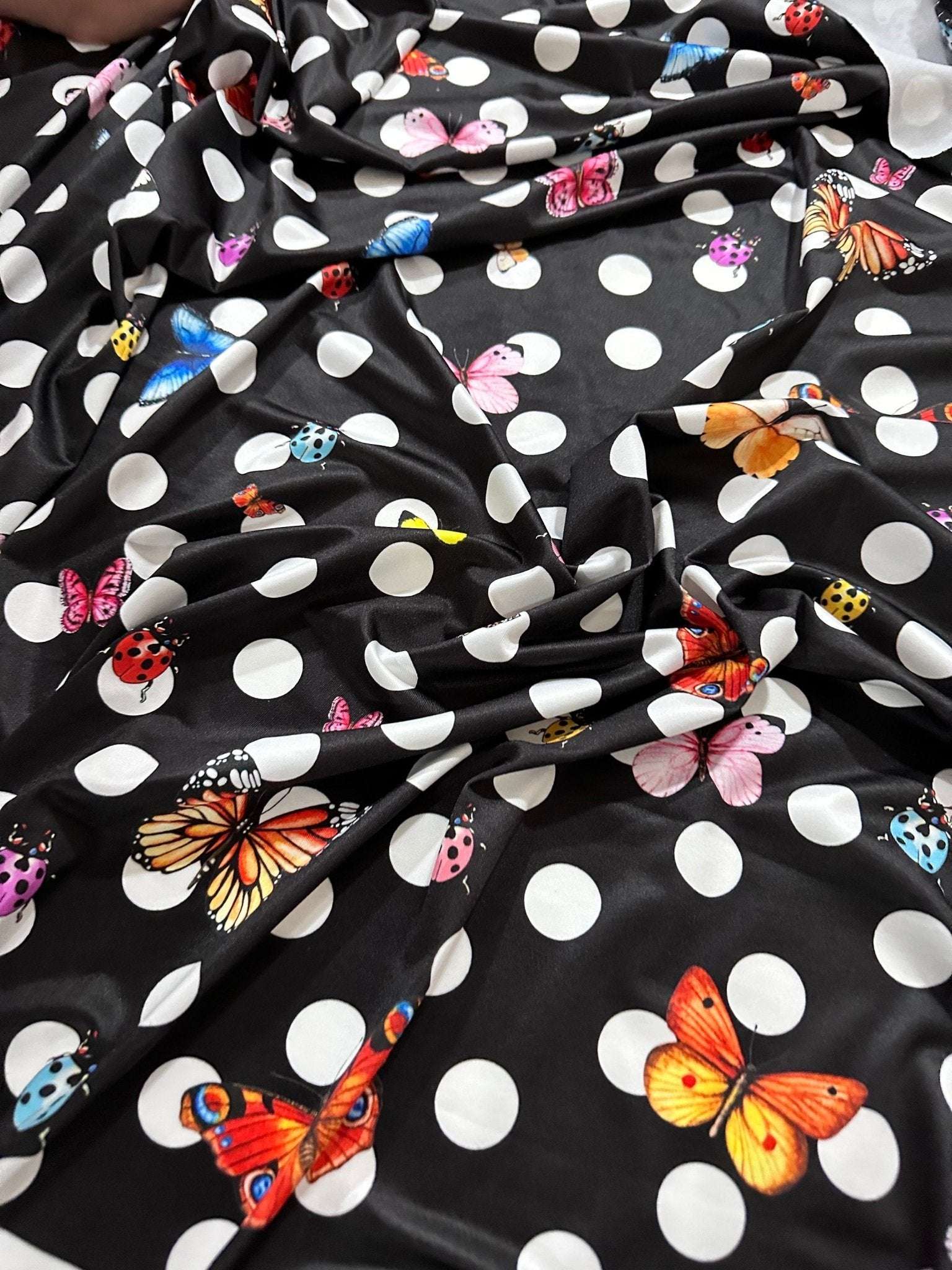 Black fabric with white polka dots and colorful butterfly designs for sewing and crafts