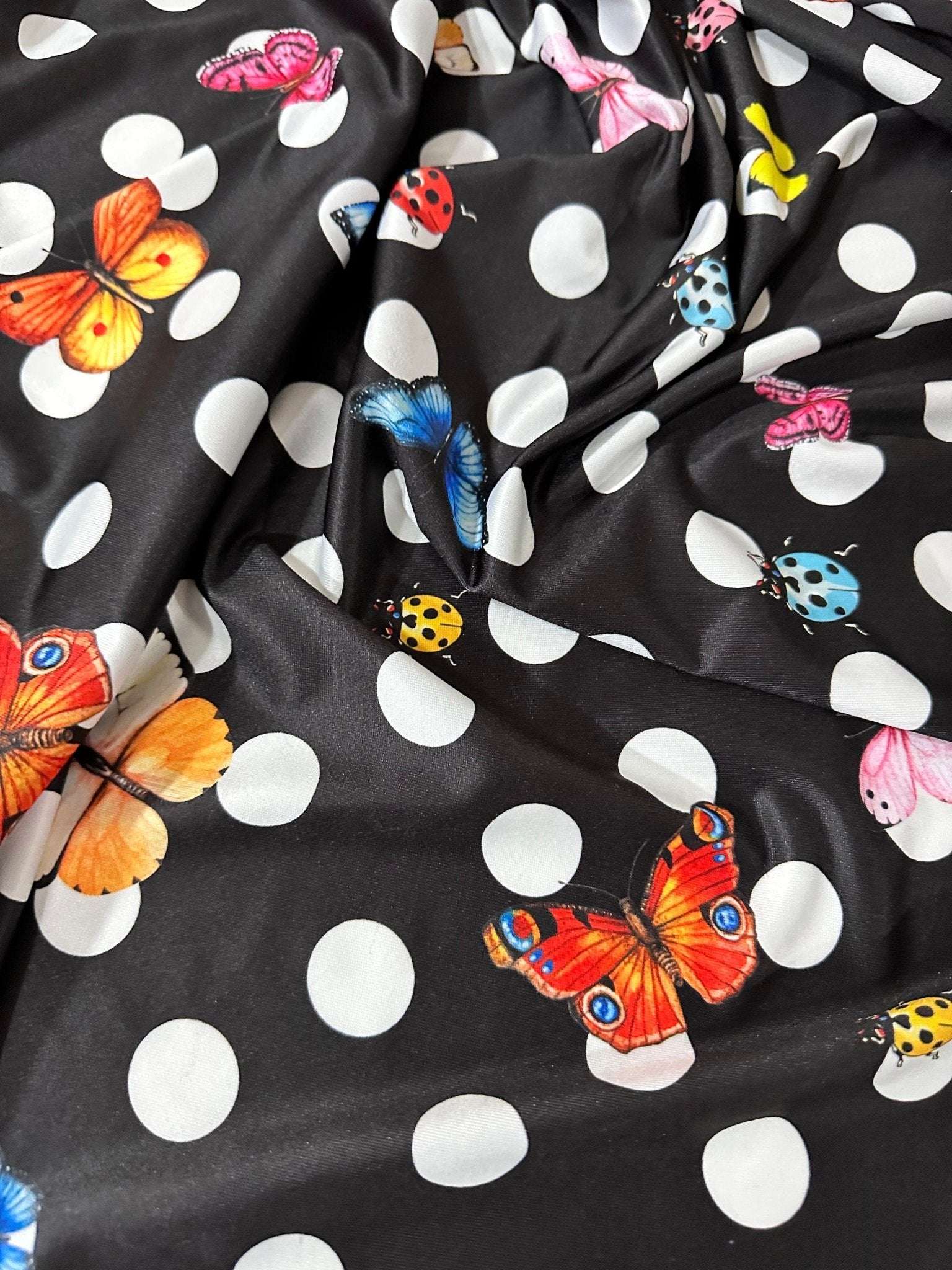 Black fabric with white polka dots and colorful butterfly prints for sewing projects