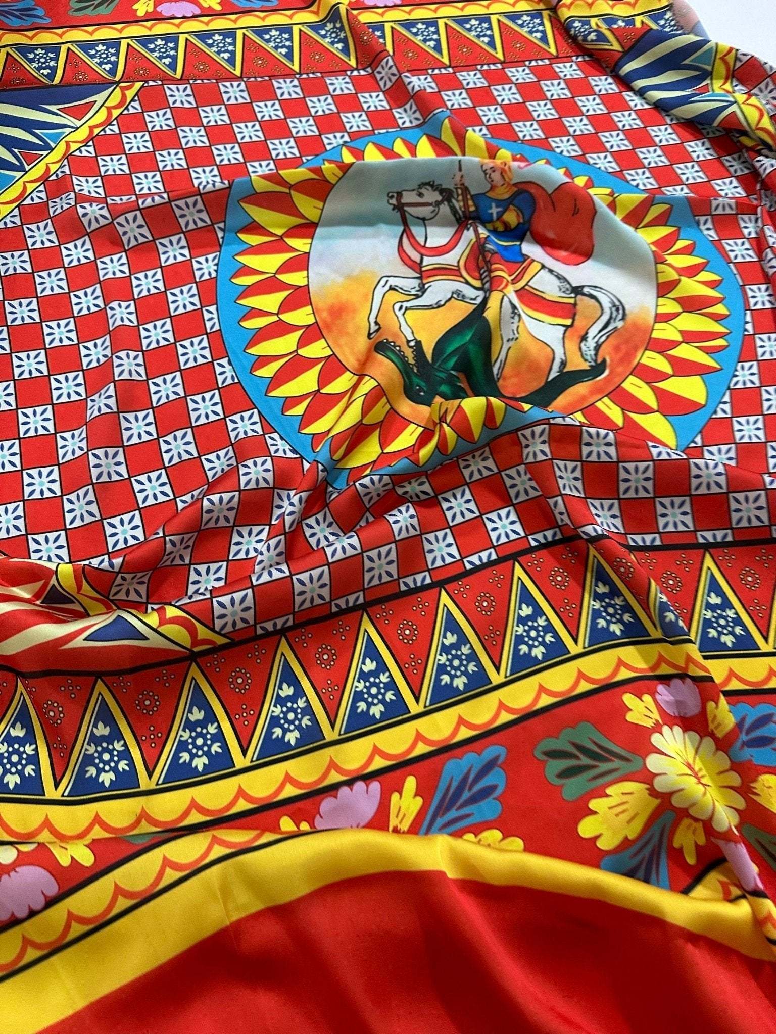 Colorful Caretto Scilly design fabric with vibrant geometric and floral patterns featuring a central horse rider motif on red background