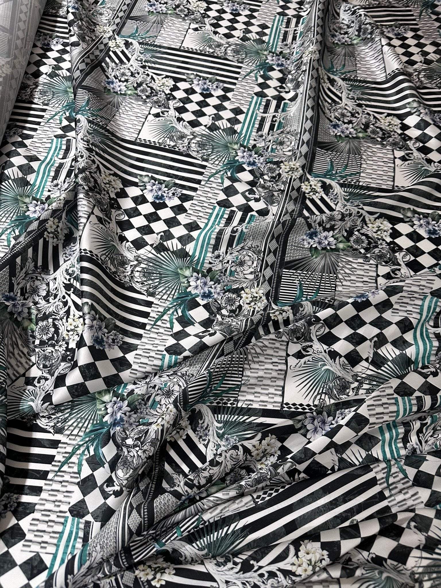 Checkerboard patchwork fabric with black, white, and teal geometric and floral patterns for quilting and crafting
