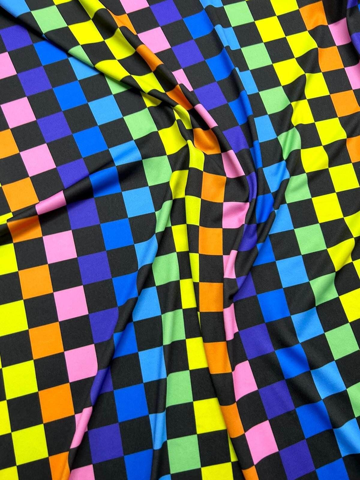 Colorful rainbow checkers print fabric with vibrant squares in multiple colors on black background, ideal for sewing and crafts