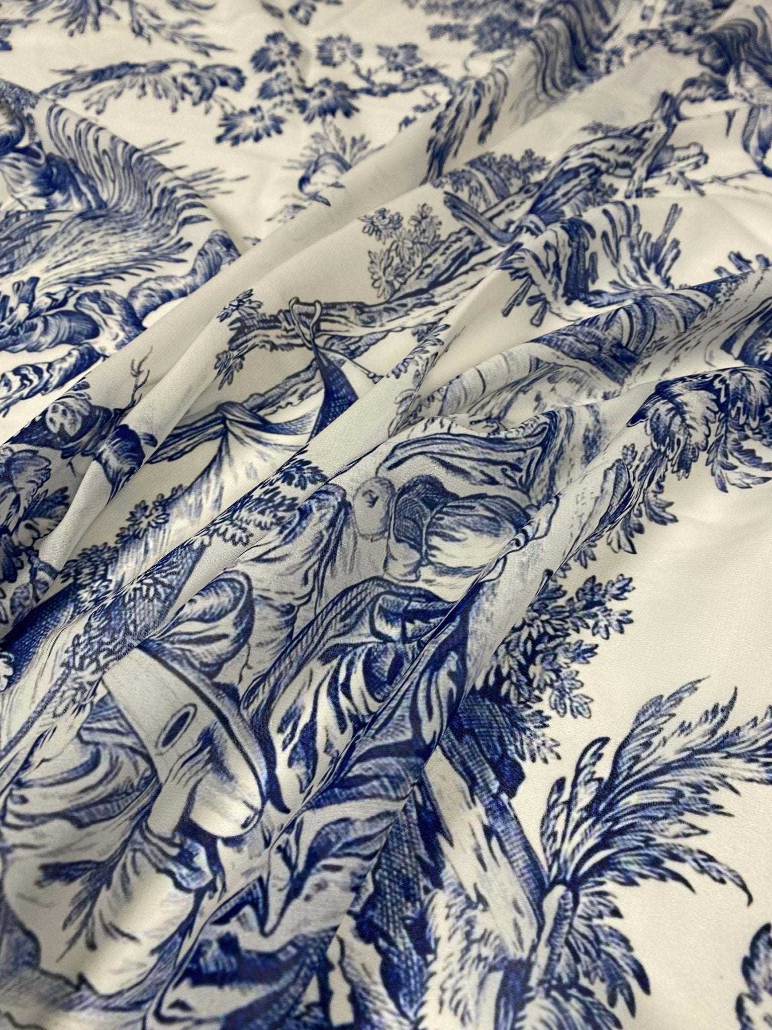 Classic Blue Toile de Jouy print fabric with intricate blue pastoral scenes on a soft white background, ideal for upholstery and home decor projects.
