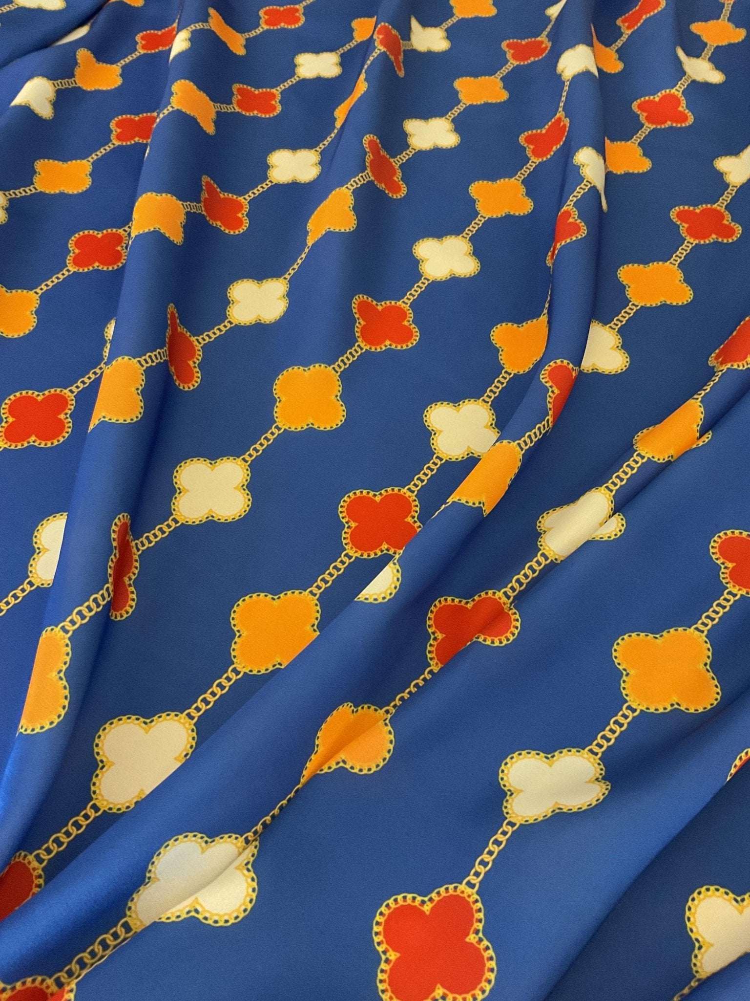 Navy blue fabric with clover chain pattern in red, orange, and cream colors, 150cm wide, suitable for sewing and quilting projects