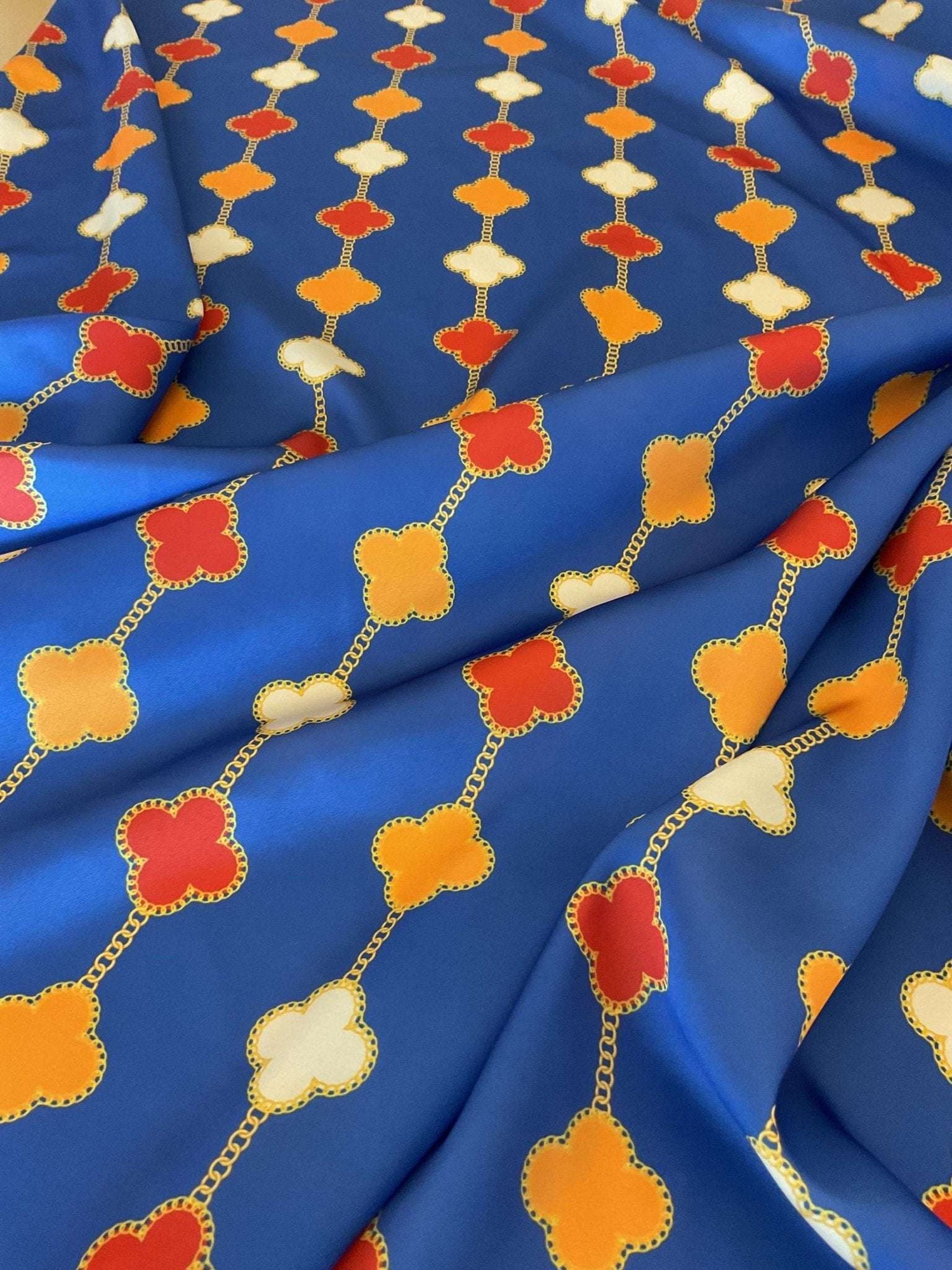 Navy blue fabric with orange, red, and white clover chain pattern for sewing and crafting projects