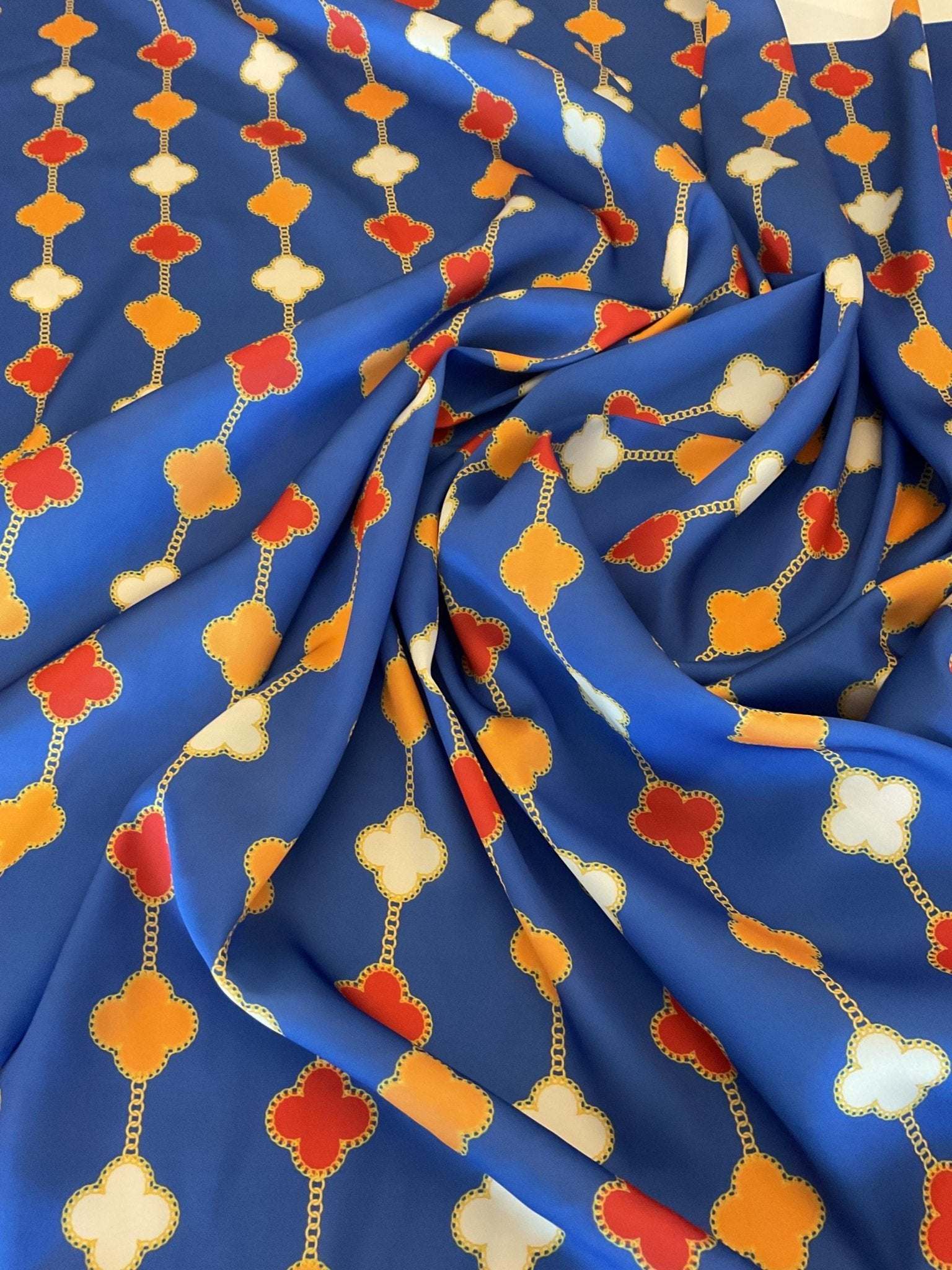 Navy blue fabric with orange, red, and white clover chain pattern and gold outlines
