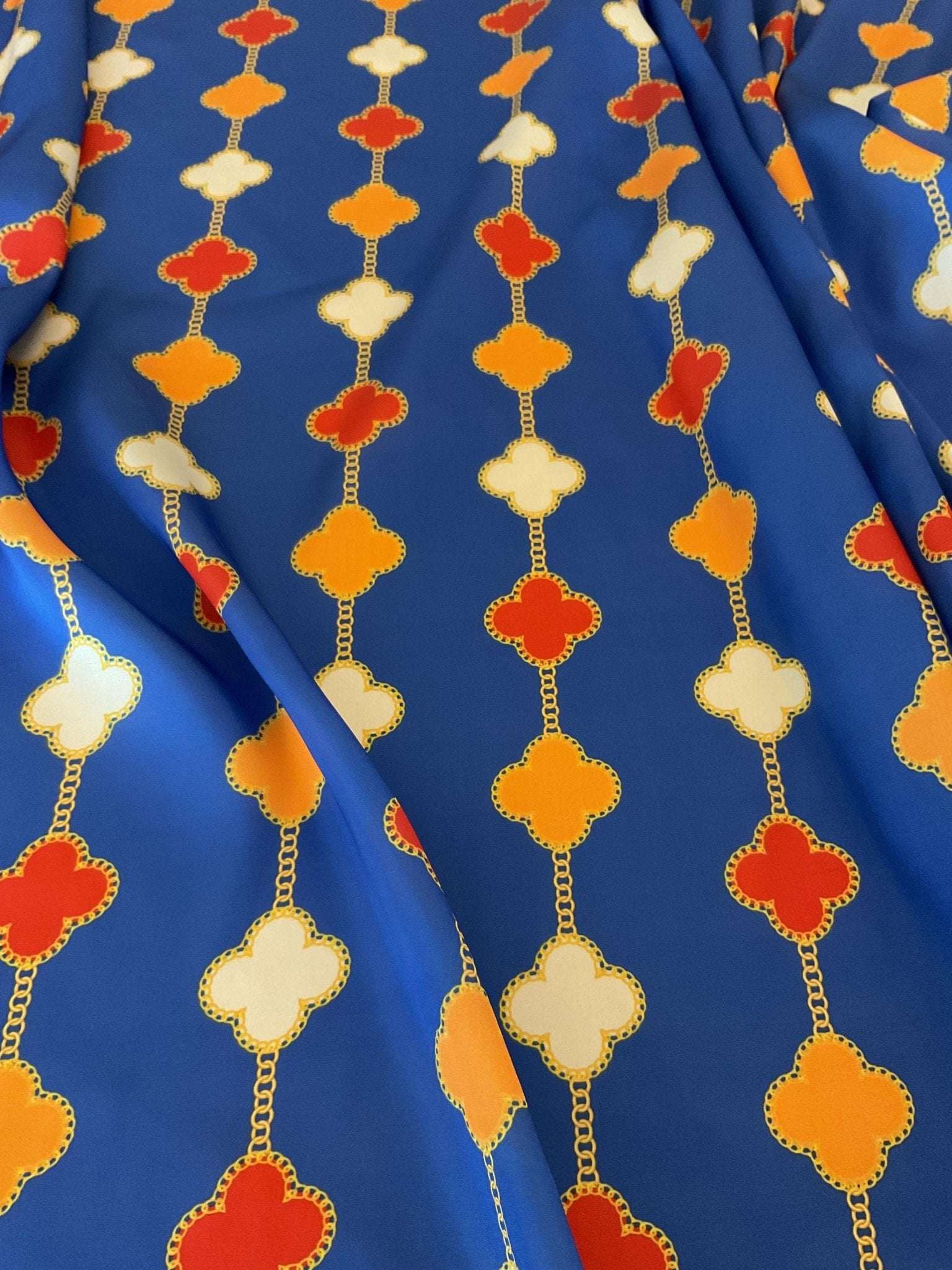 Navy blue fabric with orange, white, and red clover chain pattern
