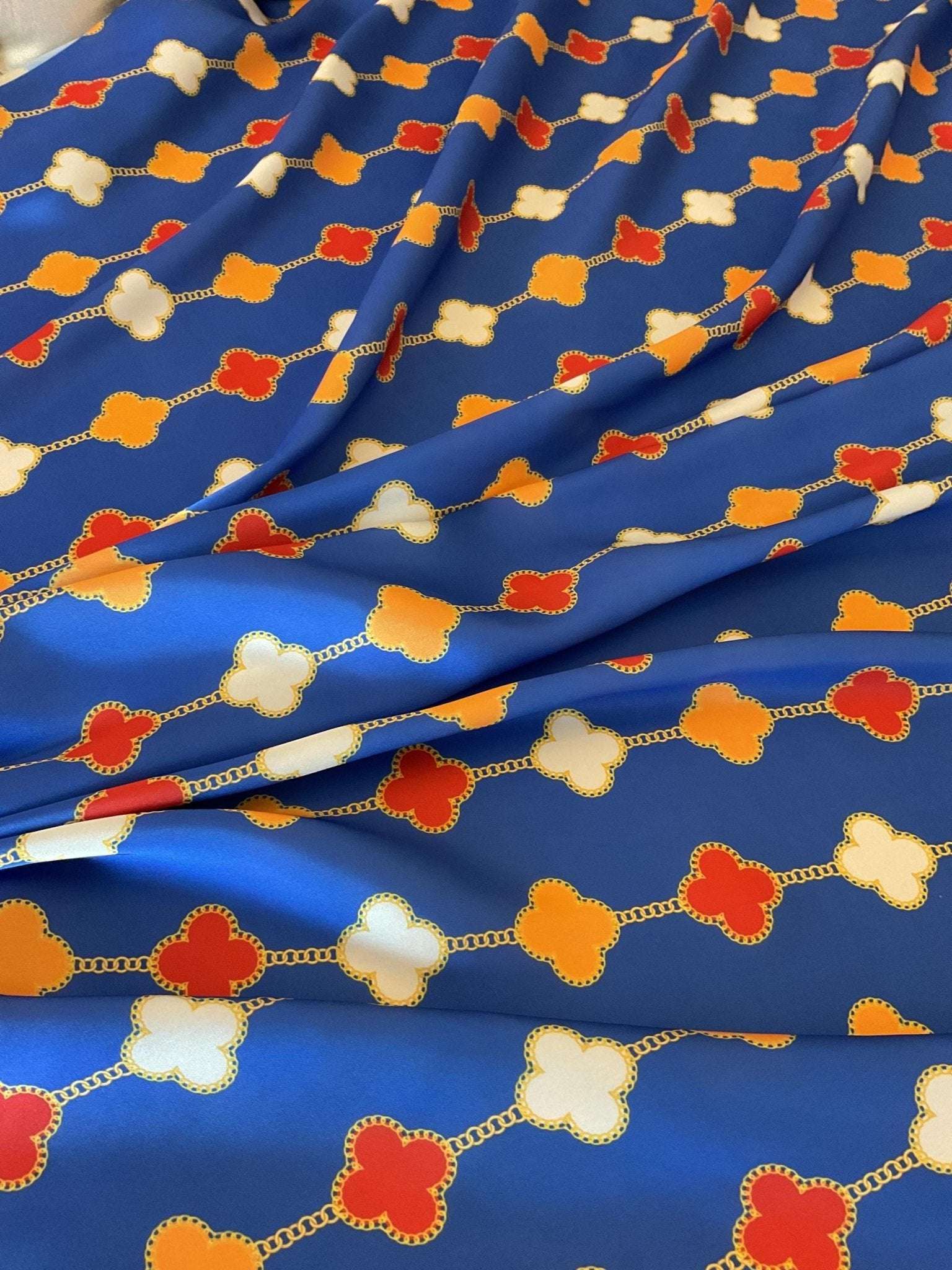 Navy blue fabric with red, white, and orange clover chain pattern, smooth texture, 150cm wide