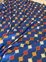 Navy blue fabric with orange, red, and white clover chain pattern, smooth texture and 150cm width