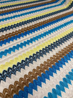 Colorful chevron embroidered fabric with green, blue, brown, and yellow zigzag knit pattern for sewing projects