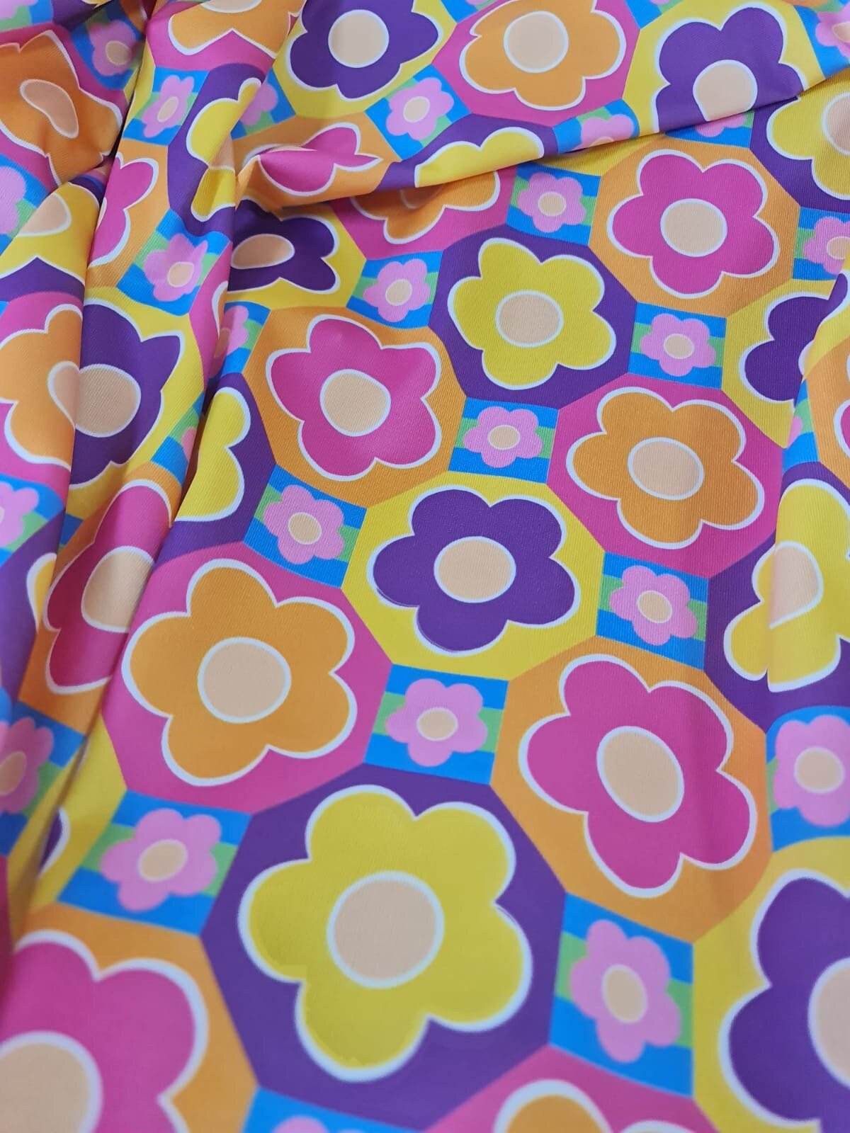 Colorful floral fabric with vibrant flower patterns in pink, yellow, purple, and orange tones, ideal for sewing and crafting projects
