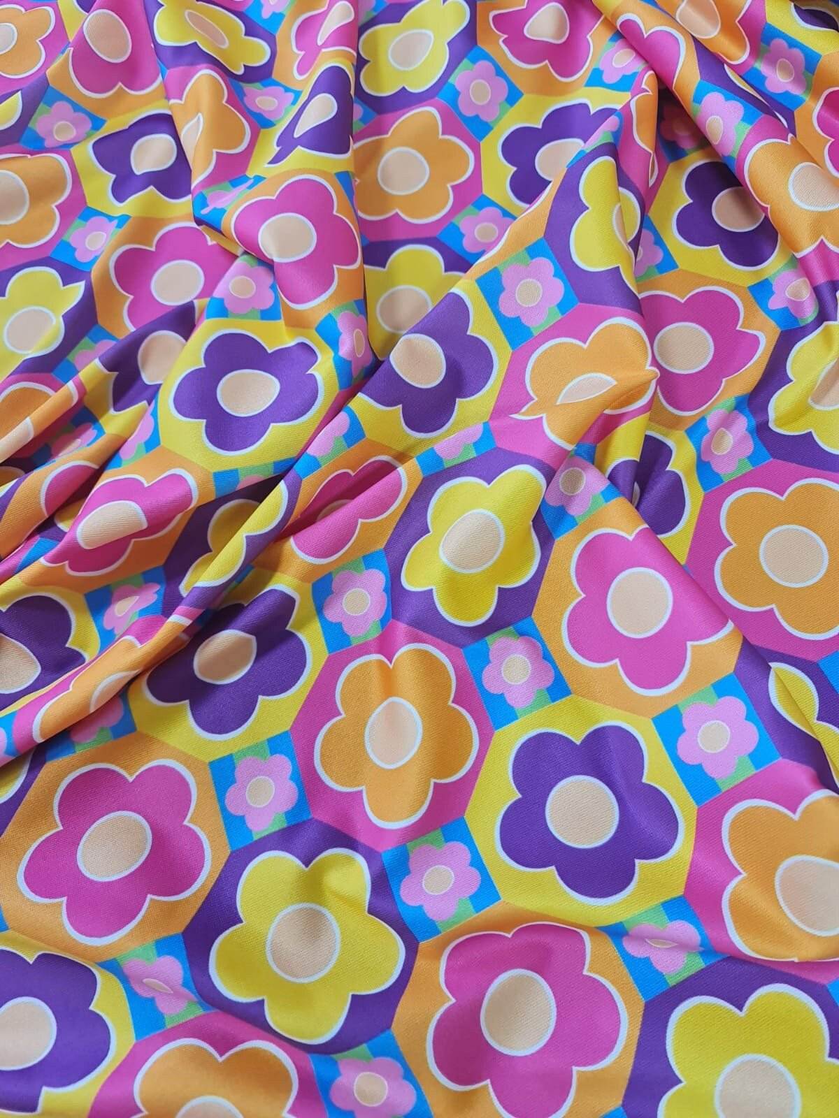 Colorful floral fabric with vibrant pink, yellow, orange, and purple flower patterns on a blue background, sold by the yard and 150cm wide