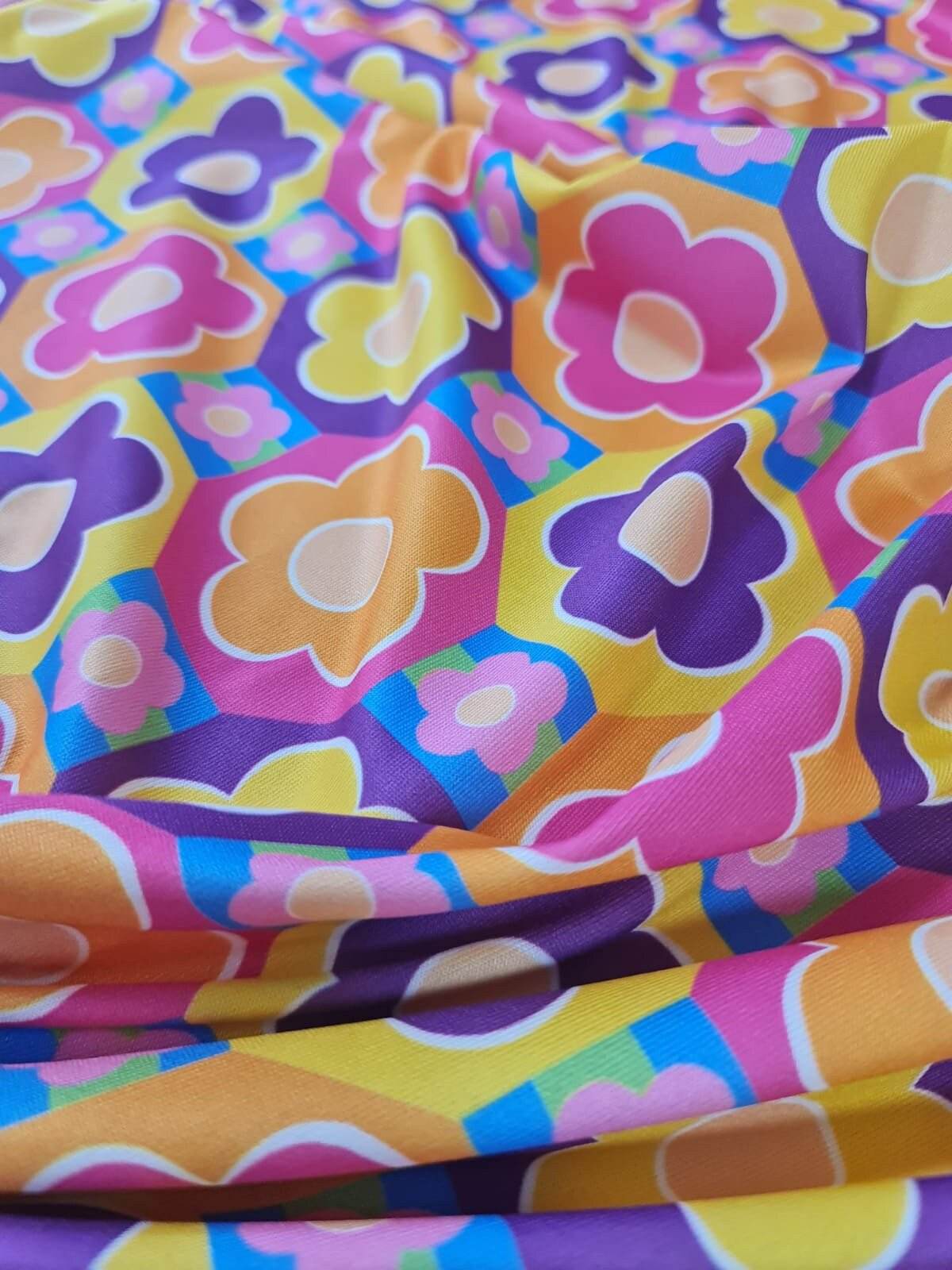 colorful floral fabric with vibrant flower patterns in pink, purple, yellow, and orange hues on a smooth textile background