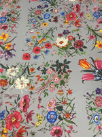 Colorful floral pattern fabric on light grey background with vibrant flowers in various colors and styles
