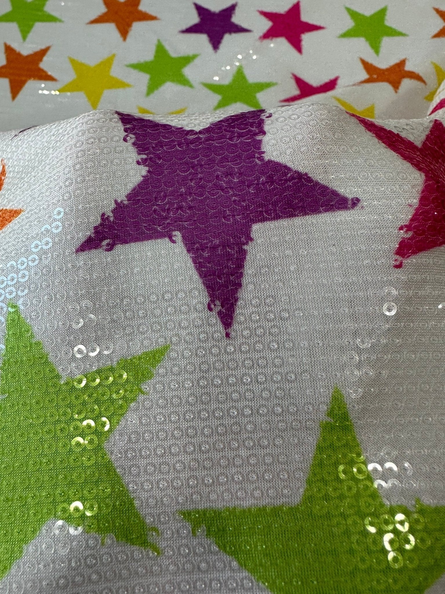 Close-up of colorful stars sequin fabric with 2-way stretch and vibrant star patterns on white background