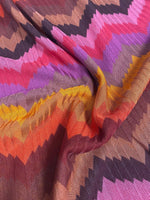 Colorful zigzag chevron pattern knit fabric with vibrant pink, purple, orange, yellow, and brown tones, ideal for sewing garments and creative projects