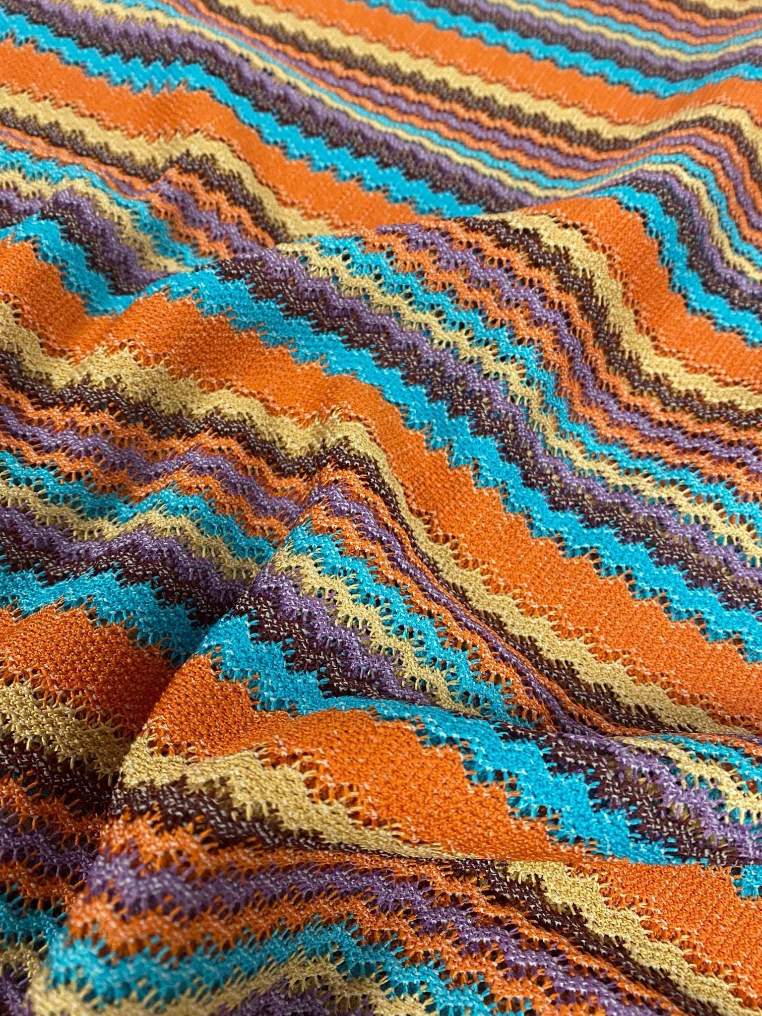 colorful zigzag stripe knit fabric in vibrant orange, blue, yellow, and brown tones with textured pattern