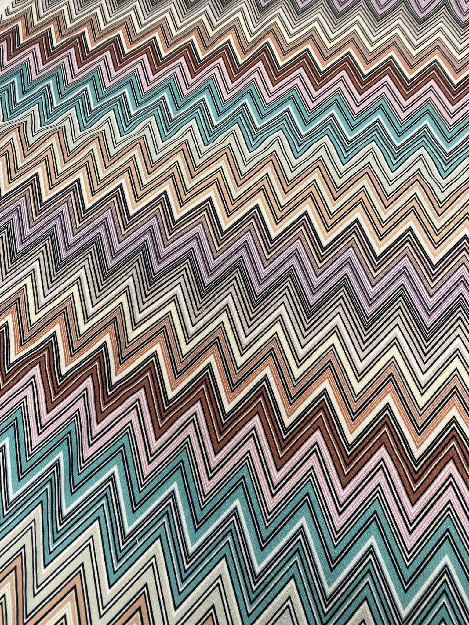 Colorful zigzag upholstery fabric with vibrant chevron pattern in teal, brown, purple, and cream for creative home décor projects