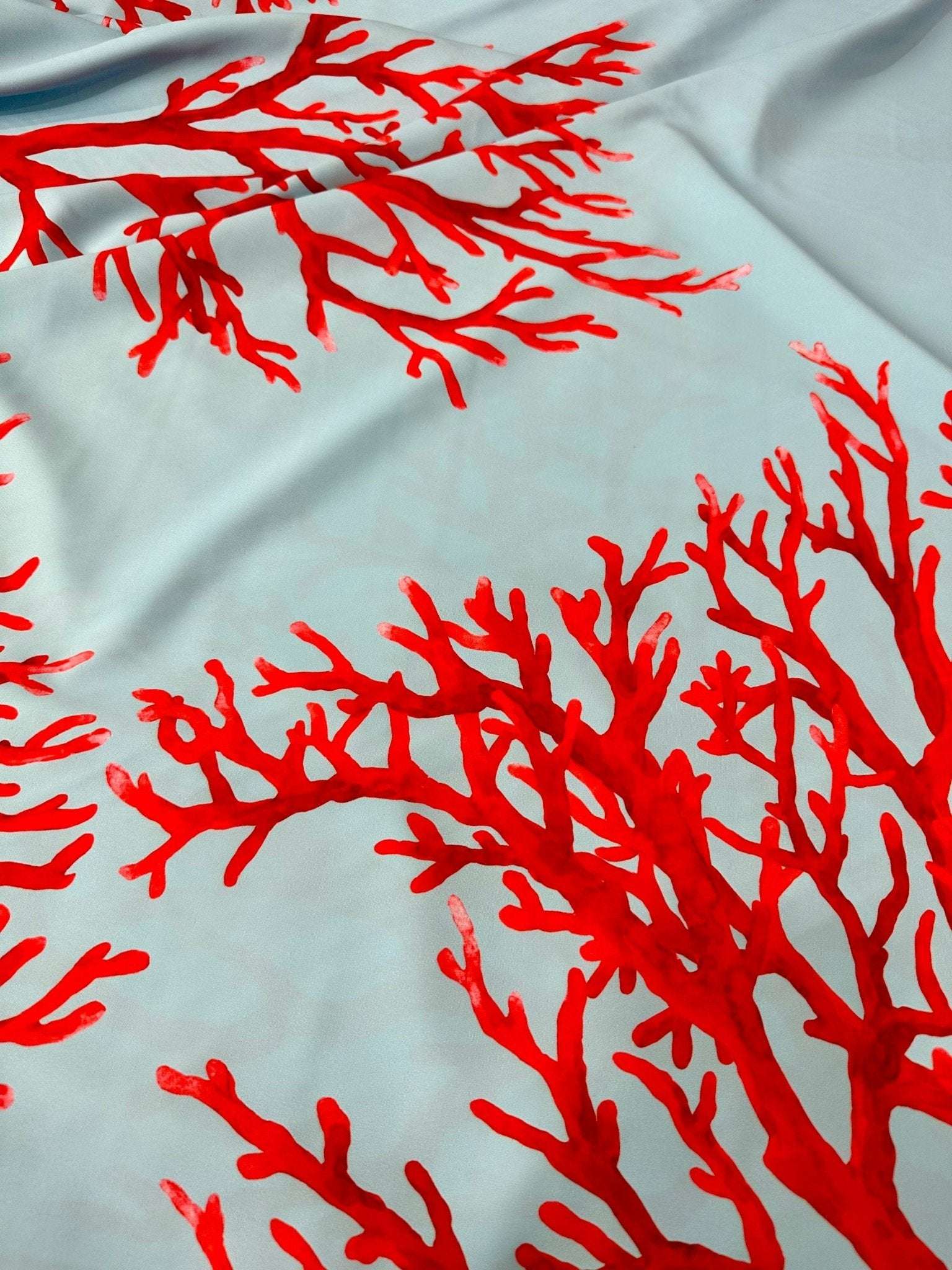 Coral pattern silky crepe fabric with vibrant red coral on light blue background, smooth texture, 150cm width
