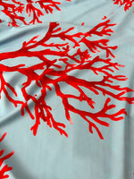 Silky crepe fabric with vibrant red coral pattern on light blue background