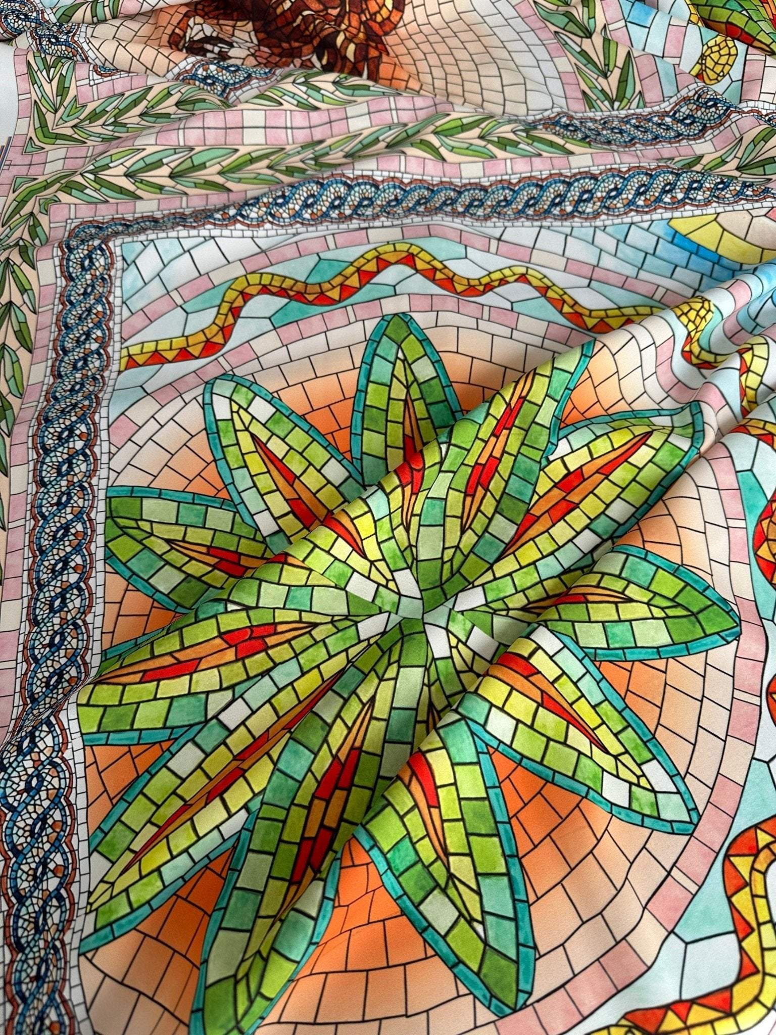 Greek mosaic print silky crepe fabric with vibrant geometric mosaic pattern in green, orange, and blue tones.