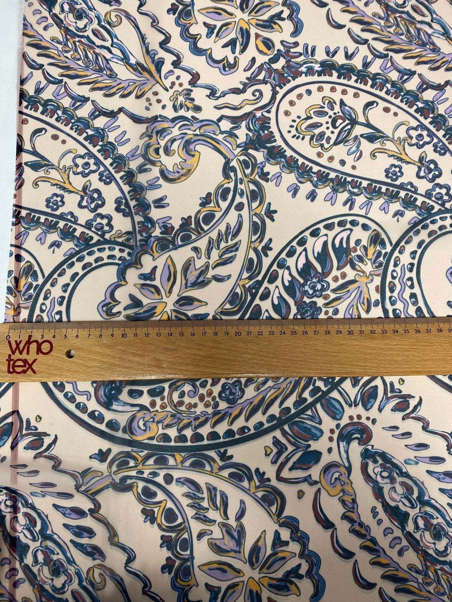 Cream background fabric with blue and yellow paisley print and measuring ruler showing scale