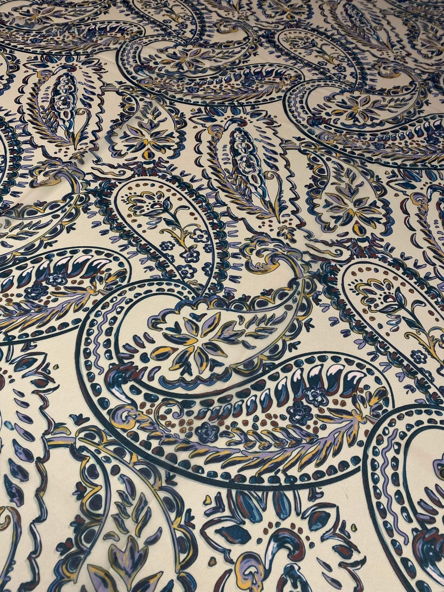 Cream background fabric with intricate blue and beige paisley print design