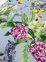 Close-up of tropical parrot print crepe fabric with colorful flowers, leaves, and bird designs on a light blue background
