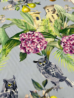 Tropical parrot print crepe fabric with vibrant parrots, tropical leaves, flowers, and owls on soft textured textile.