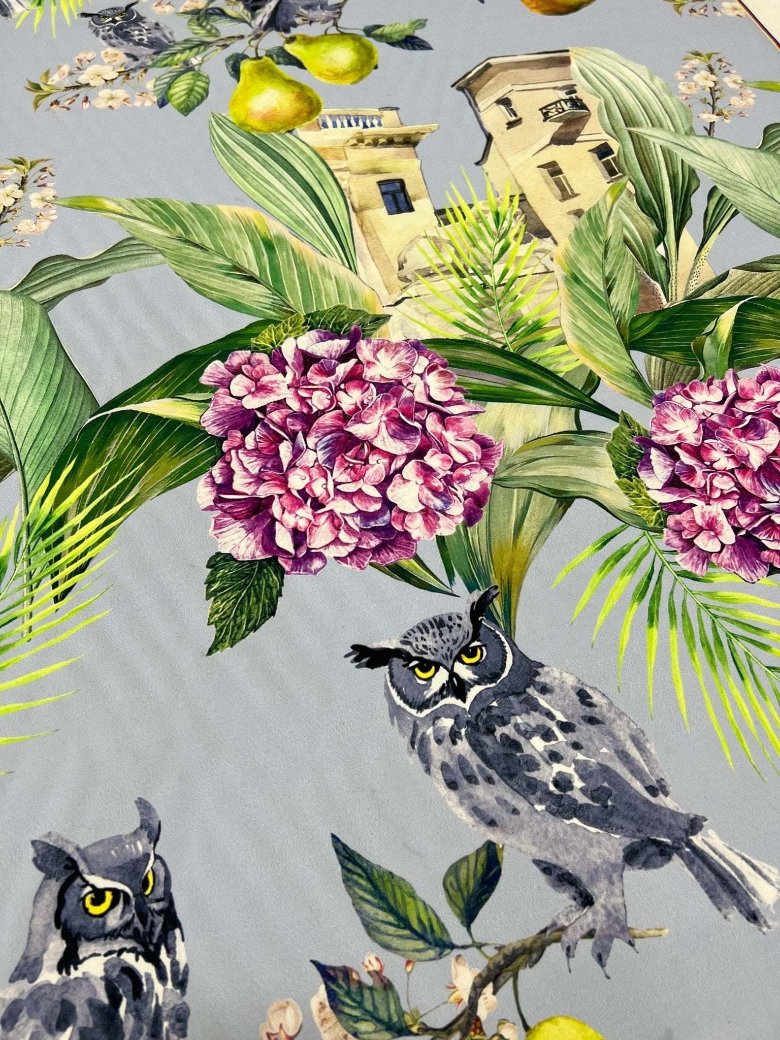 Tropical parrot print crepe fabric with vibrant parrots, tropical leaves, flowers, and owls on soft textured textile.