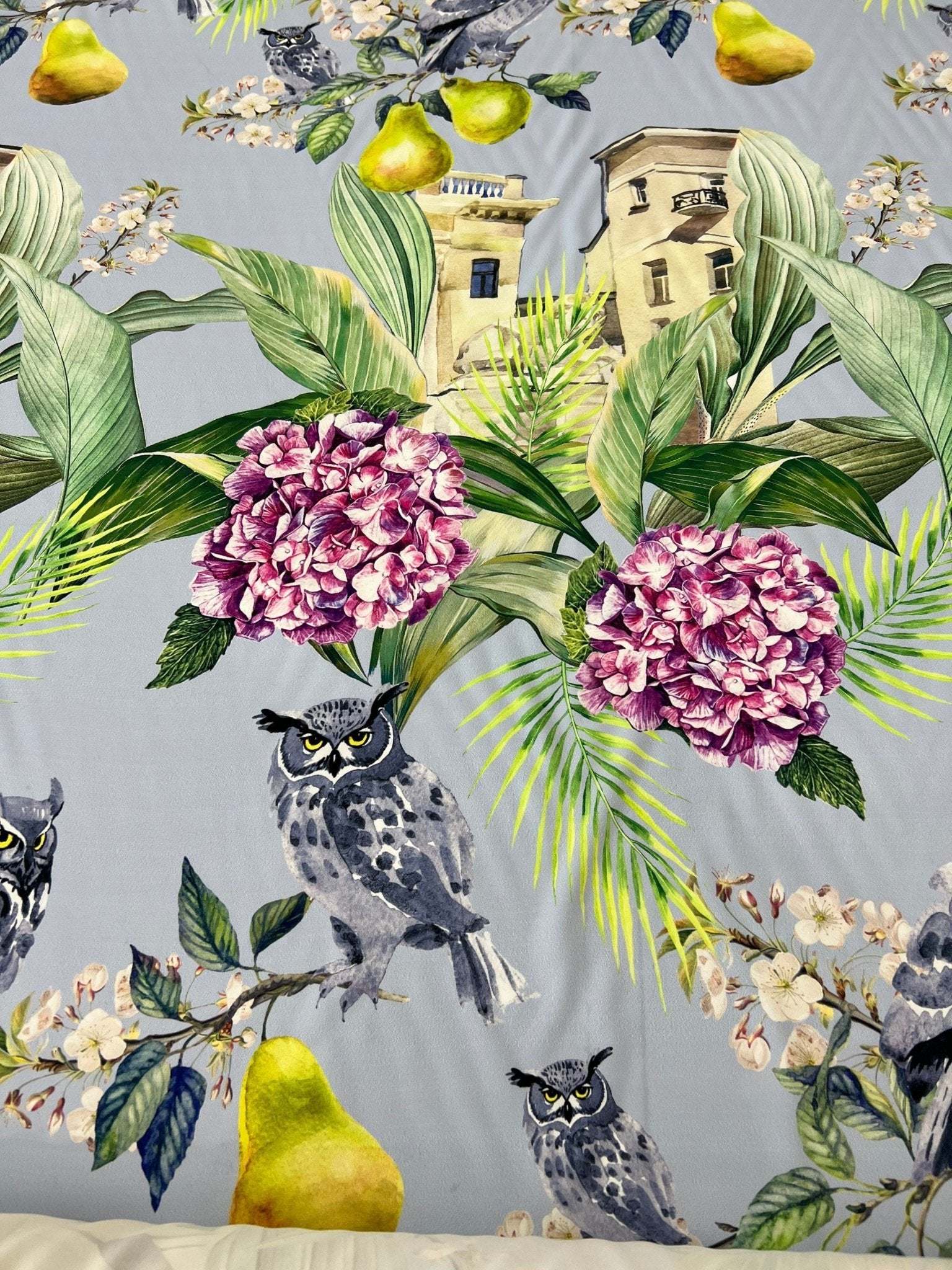 Tropical Parrot print crepe fabric with vibrant parrots, green leaves, and flowers on a gray background