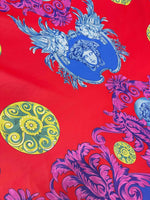 Purple swirl crepe fabric with intricate blue and yellow ornamental designs on a red background