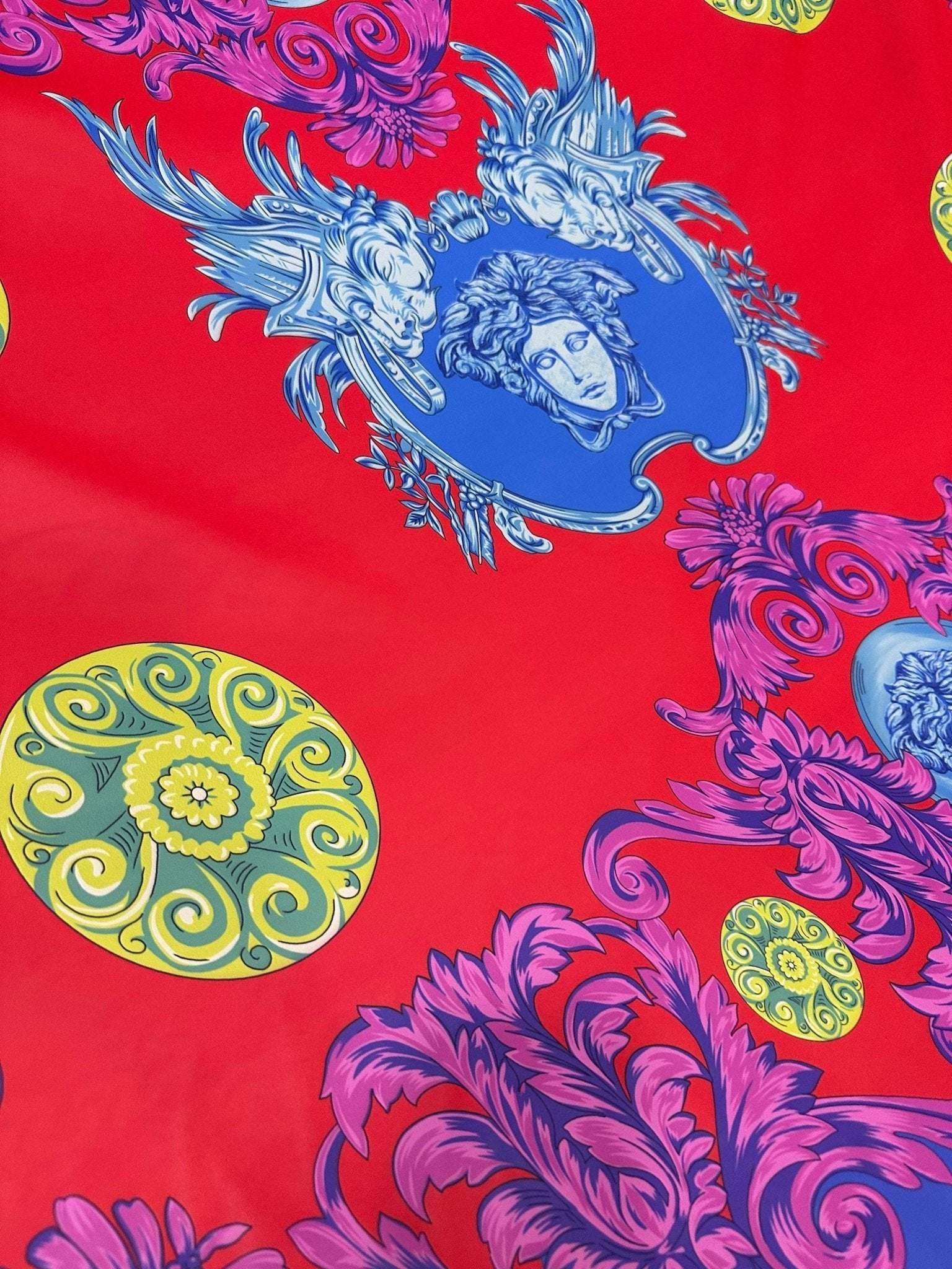 Purple swirl crepe fabric with intricate blue and yellow ornamental designs on a red background