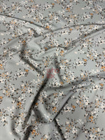 Soft fabric with delicate cherry blossom print in pastel colors on a light gray background