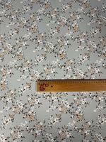 delicate cherry blossom print fabric with soft pastel floral pattern on light background and wooden ruler for scale