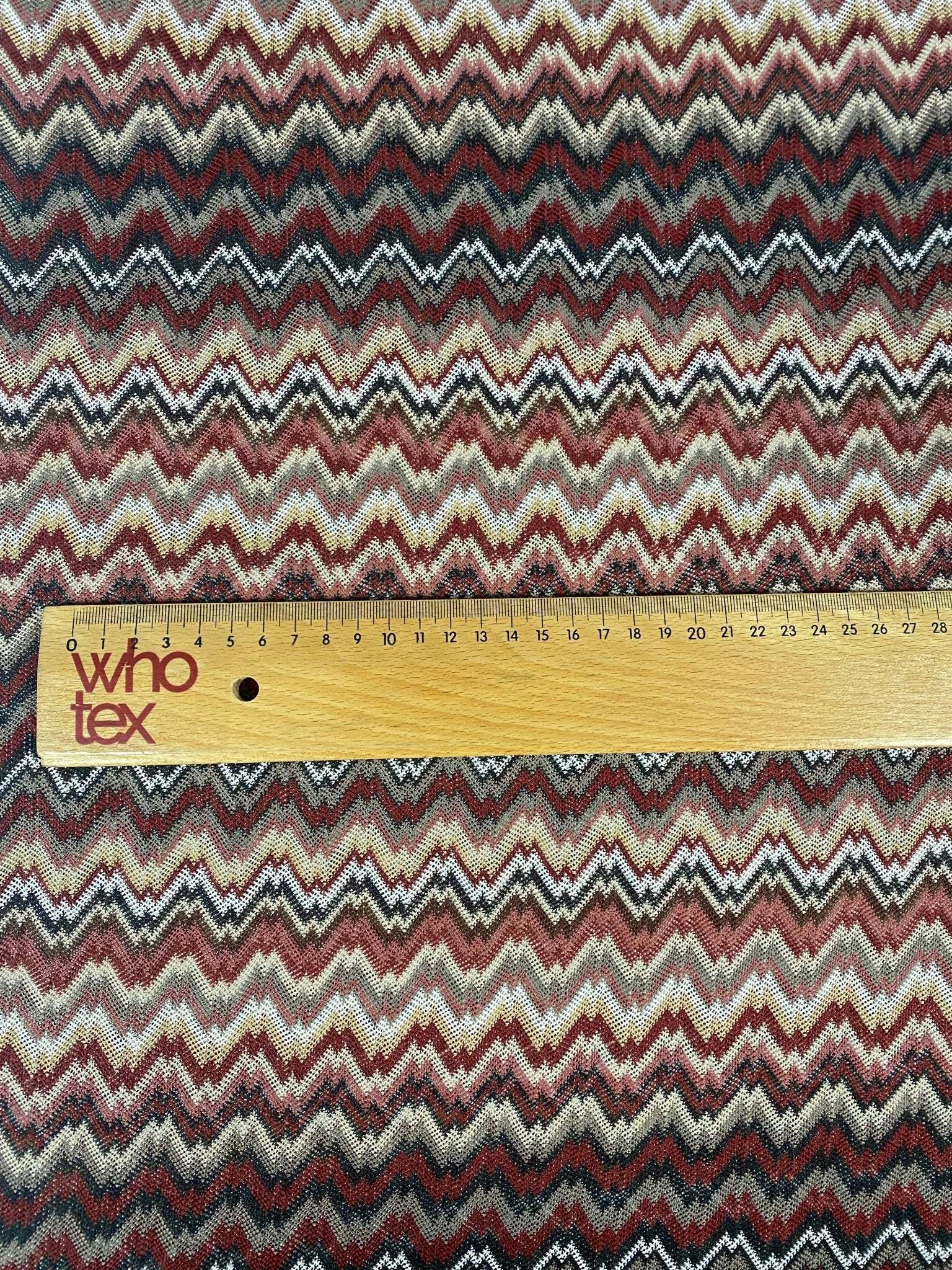 Earth tone zigzag woven mesh fabric with multicolor pattern and measuring ruler for scale