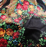 Black velvet lycra fabric with vibrant ethnic floral pattern featuring red, yellow, and blue flowers and intricate paisley designs