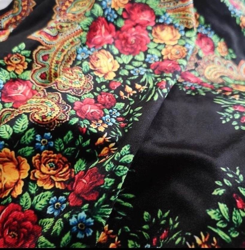 Black velvet lycra fabric with vibrant ethnic floral pattern featuring red, yellow, and blue flowers and intricate paisley designs