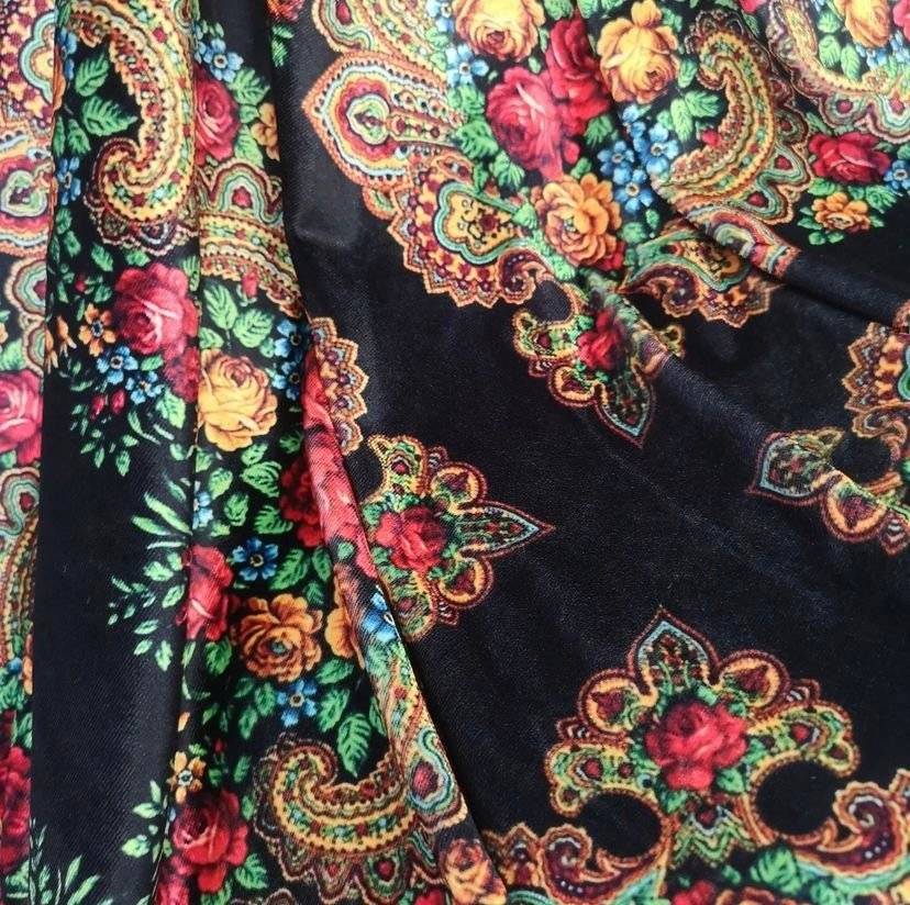 Ethnic floral pattern on soft black velvet lycra fabric with vibrant red, yellow, and blue flowers and intricate paisley designs.