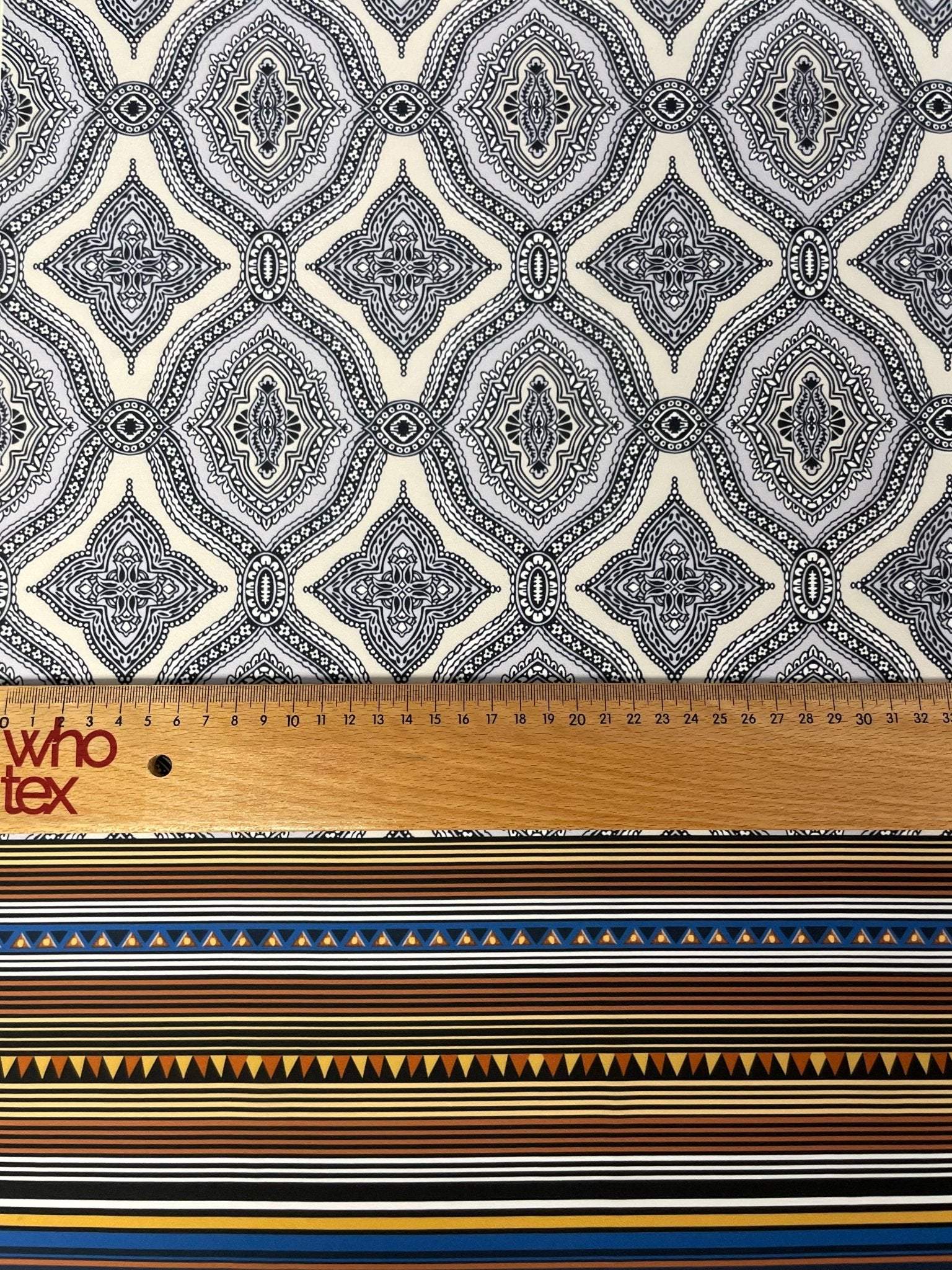 Black and white mandala pattern fabric with ethnic geometric striped border and measuring ruler for scale