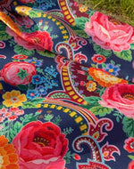 Close-up of vibrant ethnic patterned fabric with colorful floral and geometric designs on dark background, suitable for upholstery and outdoor use.