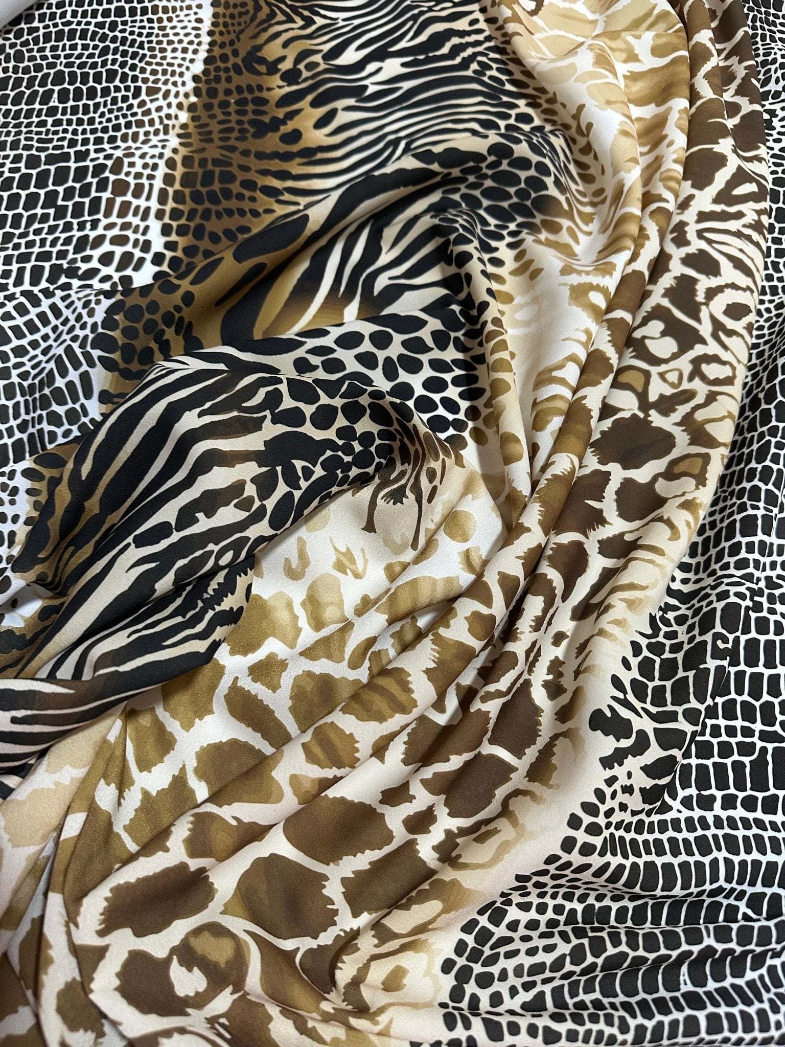 Close-up of exotic animal print fabric with zebra, giraffe, and snakeskin patterns in black, brown, and beige tones