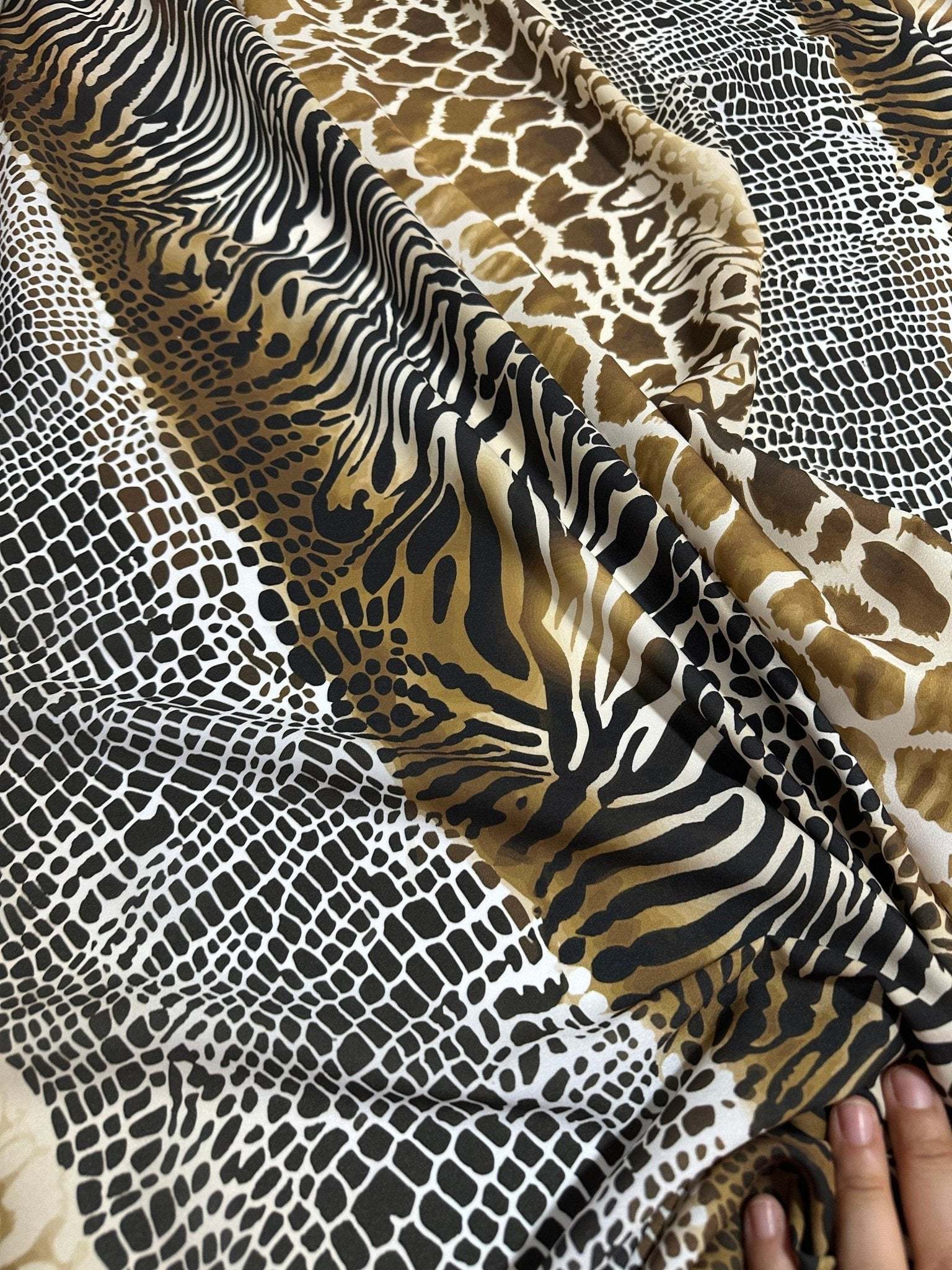 Exotic animal print fabric featuring zebra, giraffe, and snake patterns in brown, black, and beige tones with a soft texture.