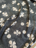 close-up of floral gold Lurex fabric with glitter knit and white floral patterns on dark background