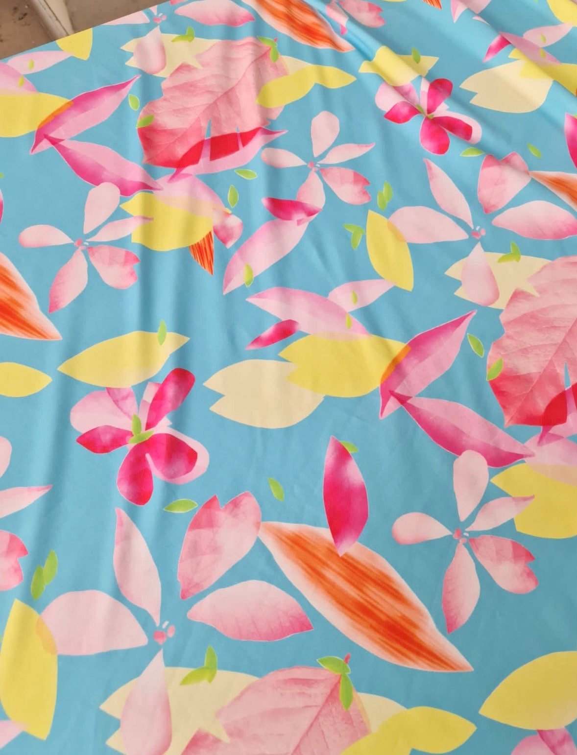 Soft cotton floral print fabric with pink, yellow, and orange flowers on a light blue background