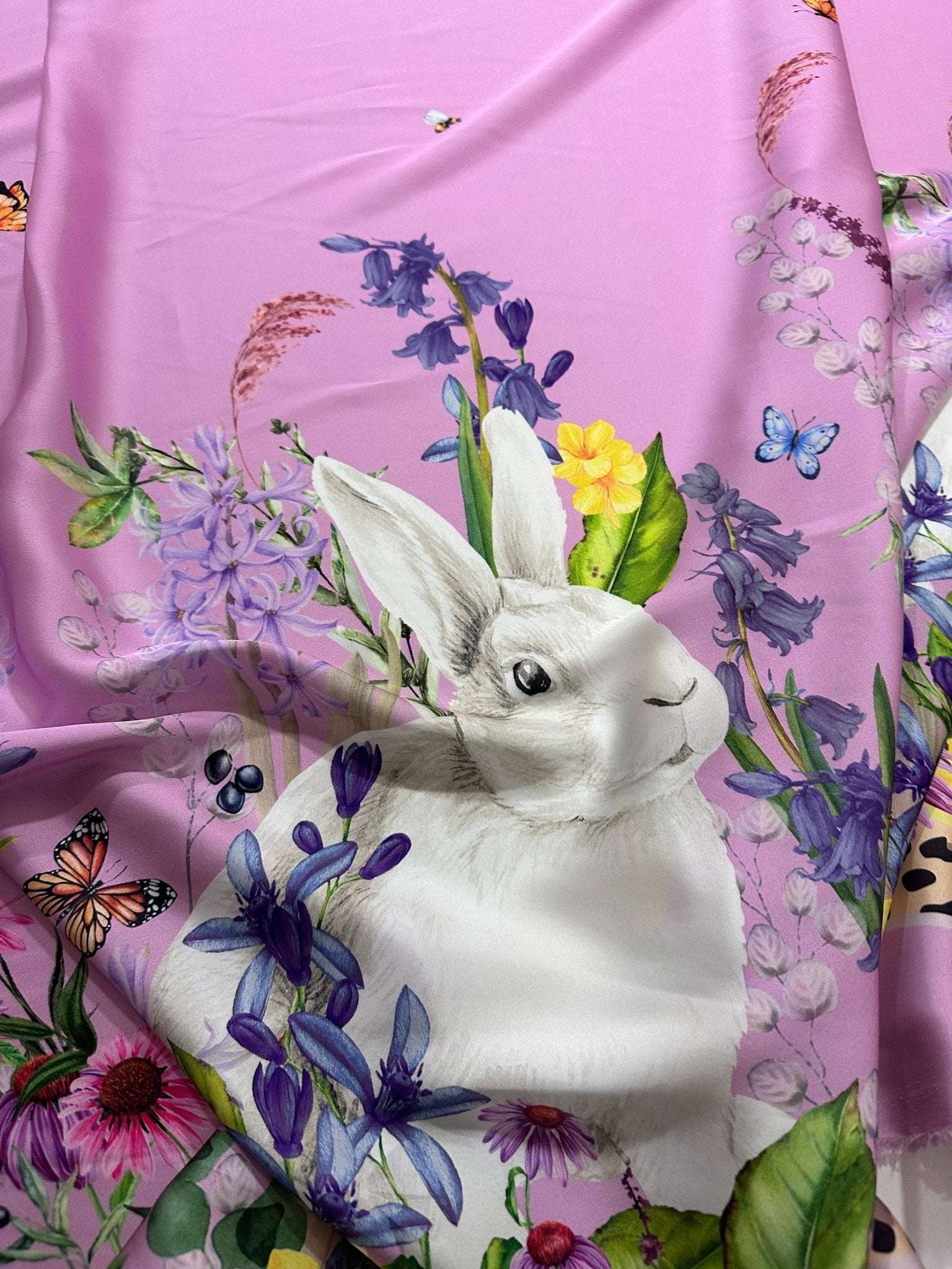 Pink fabric with white rabbit and colorful floral pattern including butterflies