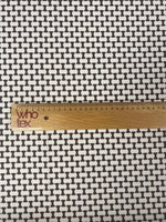 Close-up of geometric black and white optical illusion fabric with ruler showing scale