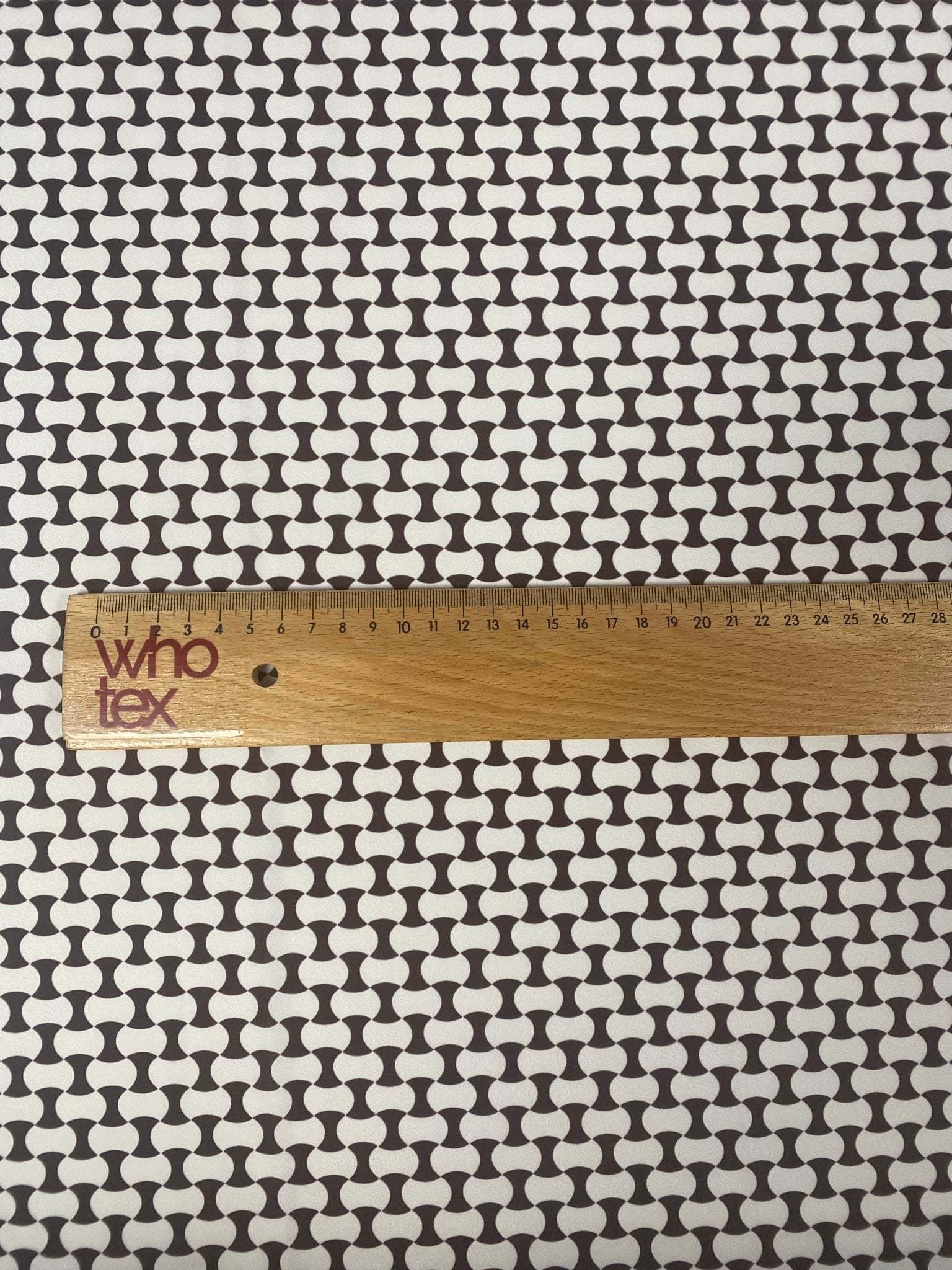 Close-up of geometric black and white optical illusion fabric with ruler showing scale