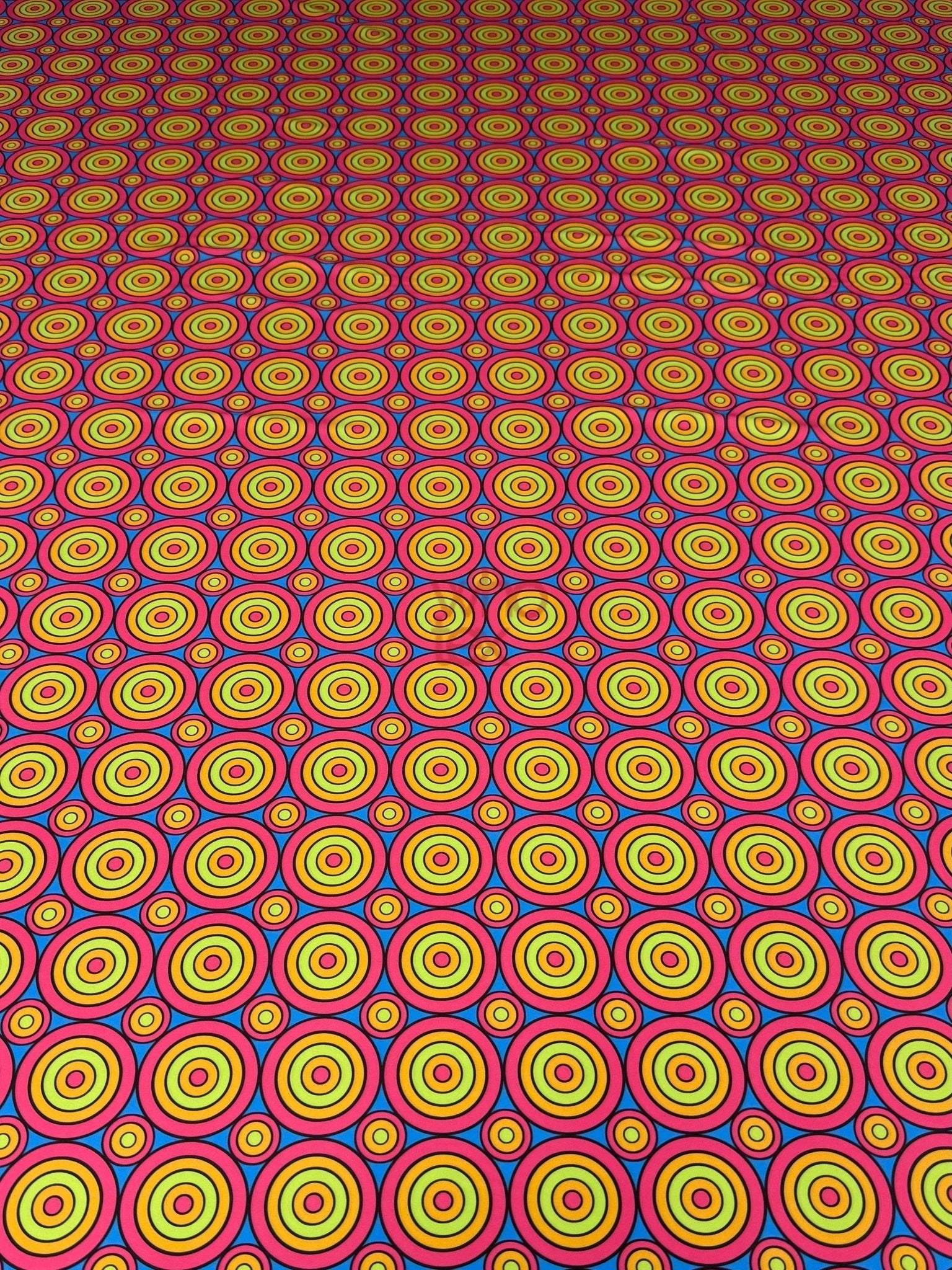 Colorful geometric circles print fabric with bright concentric circle patterns in yellow, red, and blue tones, perfect for sewing projects.