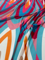 Colorful geometric print fabric with orange, pink, blue, red, and white shapes and soft texture