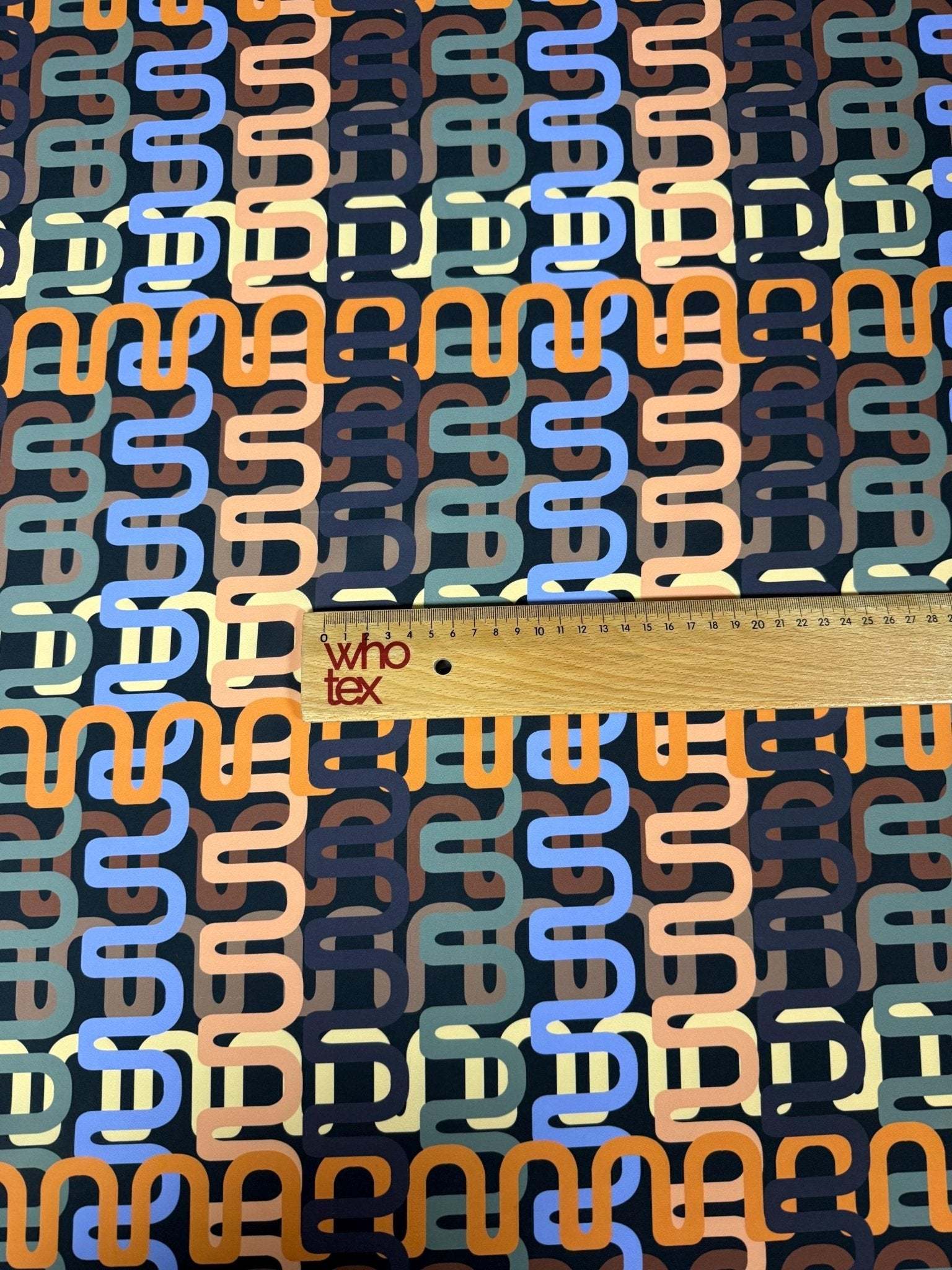 Geometric retro chain link pattern fabric in pastel tones with ruler for scale